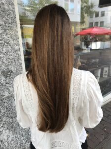 Rehbraun-hellbraune Balayage-Haarfarbe für eine glatte Langhaarfrisur, gestylt vom Friseur HappyHairHarburg in Hamburg.