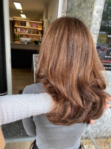 Caramel-braune Balayage-Haarfarbe für welliges, langes Haar, kreiert vom Friseur HappyHairHarburg in Hamburg.