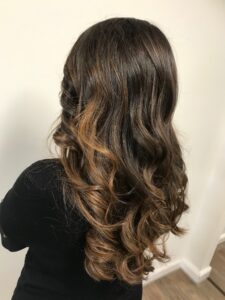 Schokolade-braune Foliage-Haarfarbe für eine wellige Langhaarfrisur, gestylt vom Friseur HappyHairHarburg in Hamburg.