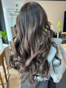 Dunkel-braune Balayage-Haarfarbe für eine wellige Langhaarfrisur, gestylt vom Friseur HappyHairHarburg in Hamburg.