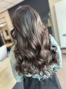 Dunkel-braune Balayage-Haarfarbe für eine wellige Langhaarfrisur, gestylt vom Friseur HappyHairHarburg in Hamburg.