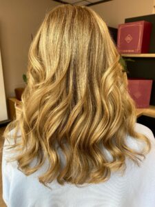 Caramel-goldblondes Balayage für welliges, langes Haar mit Redken-Produkten beim Friseur in Hamburg. #caramelgoldblond #balayage #langeswelligeshaar