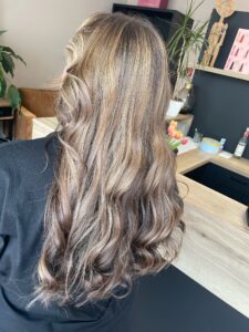 Caramelbraune Foliage-Strähnchen auf welligem, langem Haar mit Schwarzkopf-Produkten.