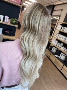 Aschblonde und goldblonde weiße Haarfarbe mit Balayage-Technik für lange, wellige Haare, gestylt vom Friseur HappyHairHarburg in Hamburg.