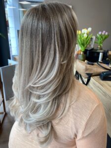 Platin-aschblonde weiße Haarfarbe mit Balayage-Technik für lange, wellige Haare, gestylt vom Friseur HappyHairHarburg in Hamburg.