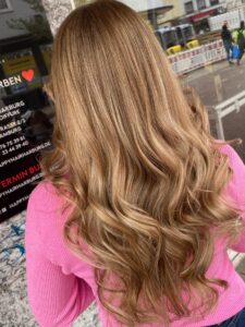 Dunkel goldblondes, welliges Langhaar mit Balayage-Technik und Wella-Produkten für eine Geburtstagsfeier in Hamburg im Frühling 2024. #dunkelgoldblondeshaar #welligeslanghaar #balayagetechnik #geburtstagsfeierhamburg