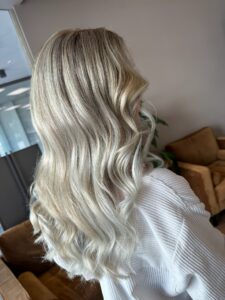 Platin-blonde weiße Haarfarbe mit Balayage-Technik für lange, wellige Haare, gestylt vom Friseur HappyHairHarburg in Hamburg.