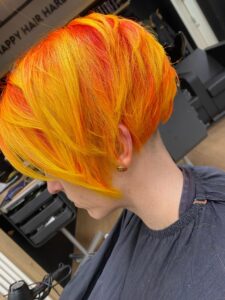 Entdecke die strahlenden Farben von Orange Yellow! 🍊💛 Eine aufregende Haarfarbe mit balayage Technik, perfekt für den Frühling 2024. Pixie-Cut mit welligem Haar für einen einzigartigen Look. Friseur: HappyHairHarburg.